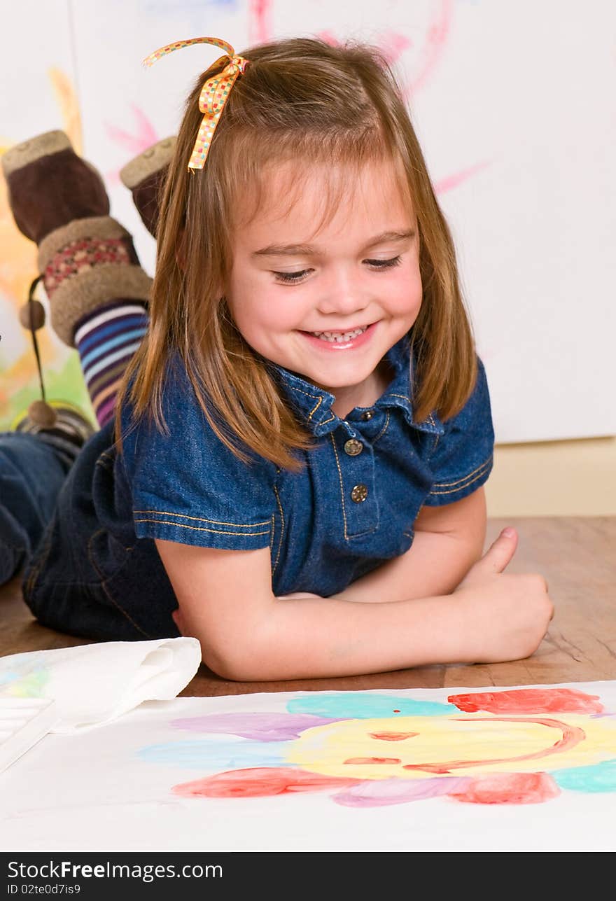 Smiling little girl looking at her art work. Smiling little girl looking at her art work