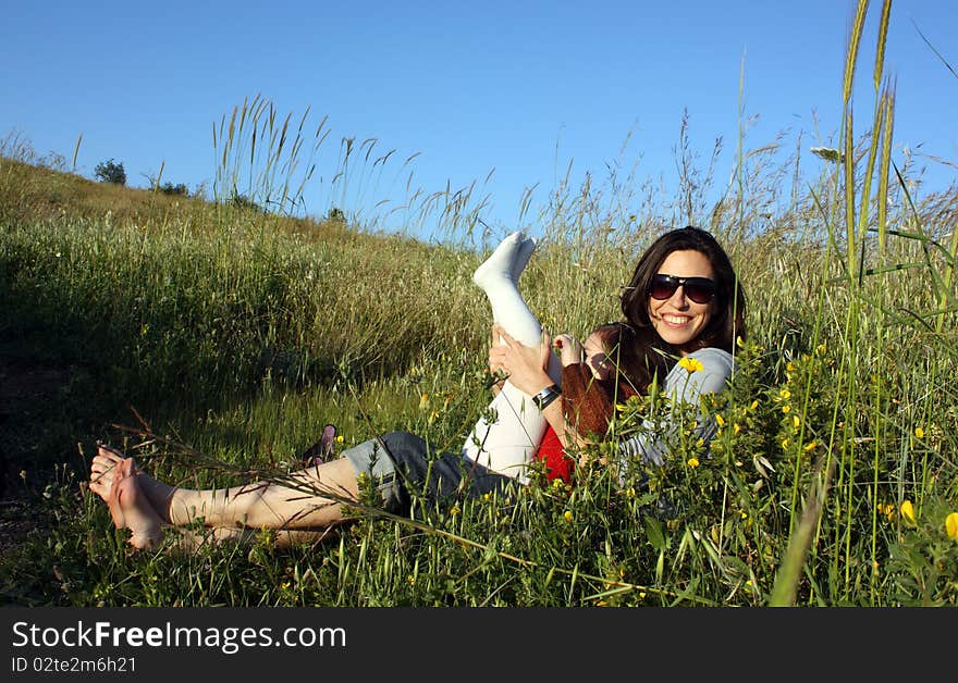 Young mother and daughter sitting on the grass. Autumn.