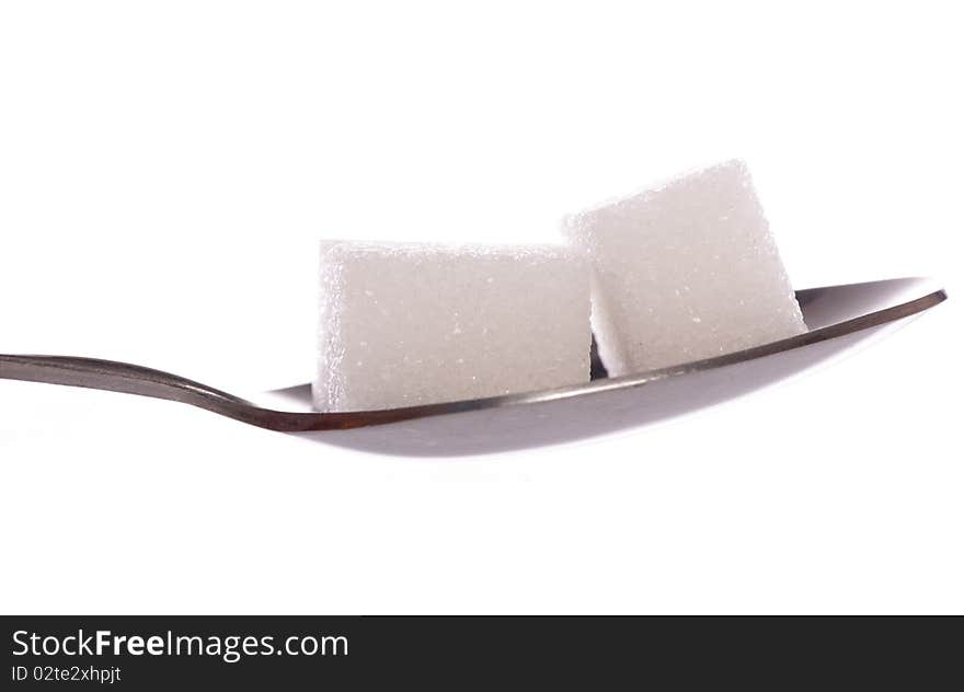 Two white sugar cubes on tea spoon