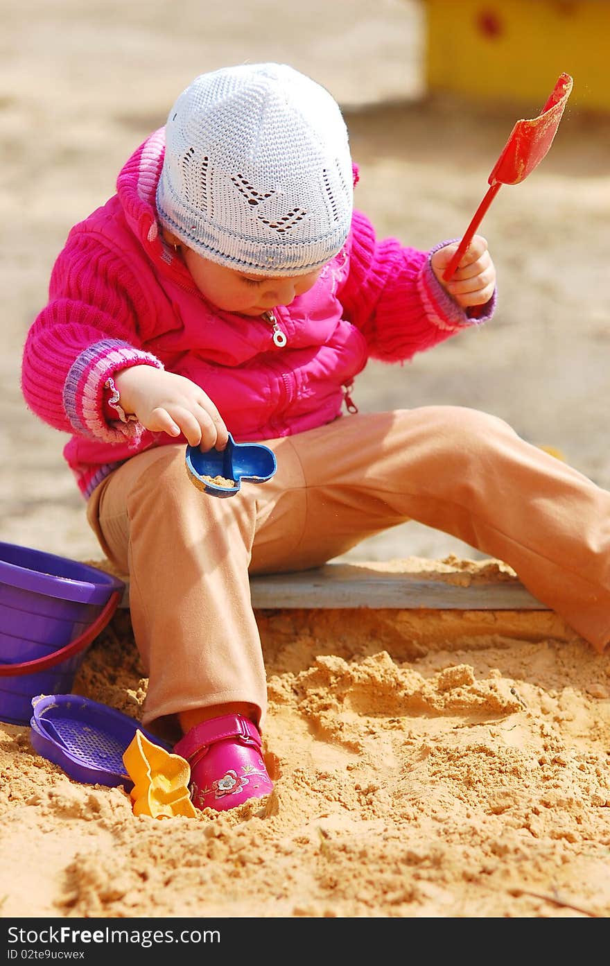 The little girl in a sandbox in a sunny day