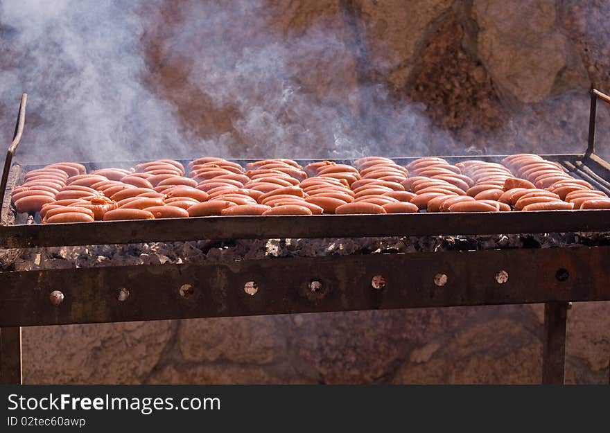 Sausages cooking on the grill in the background . Sausages cooking on the grill in the background .