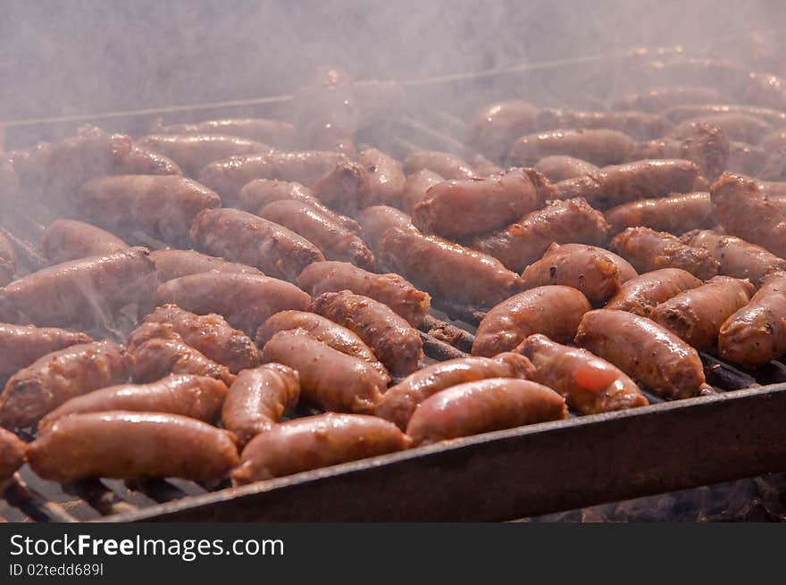 Sausages cooking on the grill in the background . Sausages cooking on the grill in the background .