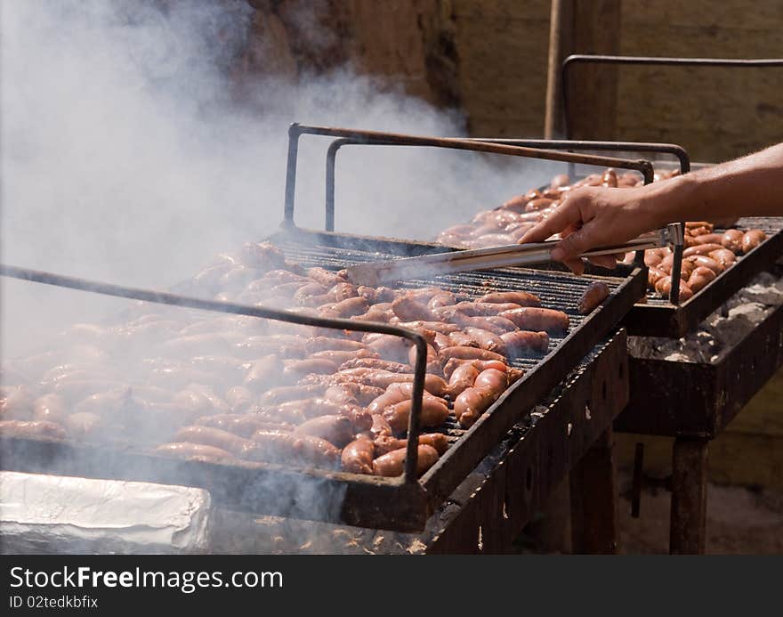 Sausages cooking on the grill in the background . Sausages cooking on the grill in the background .