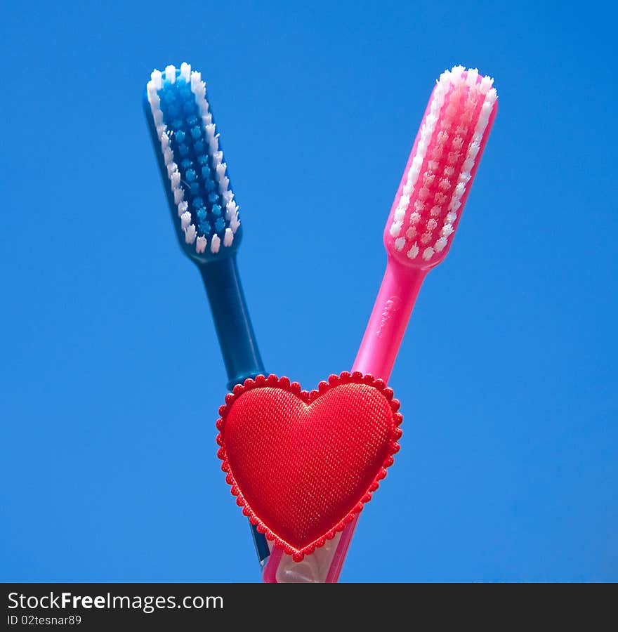 Two toothbrushes as a sign of love against a blue sky. Two toothbrushes as a sign of love against a blue sky