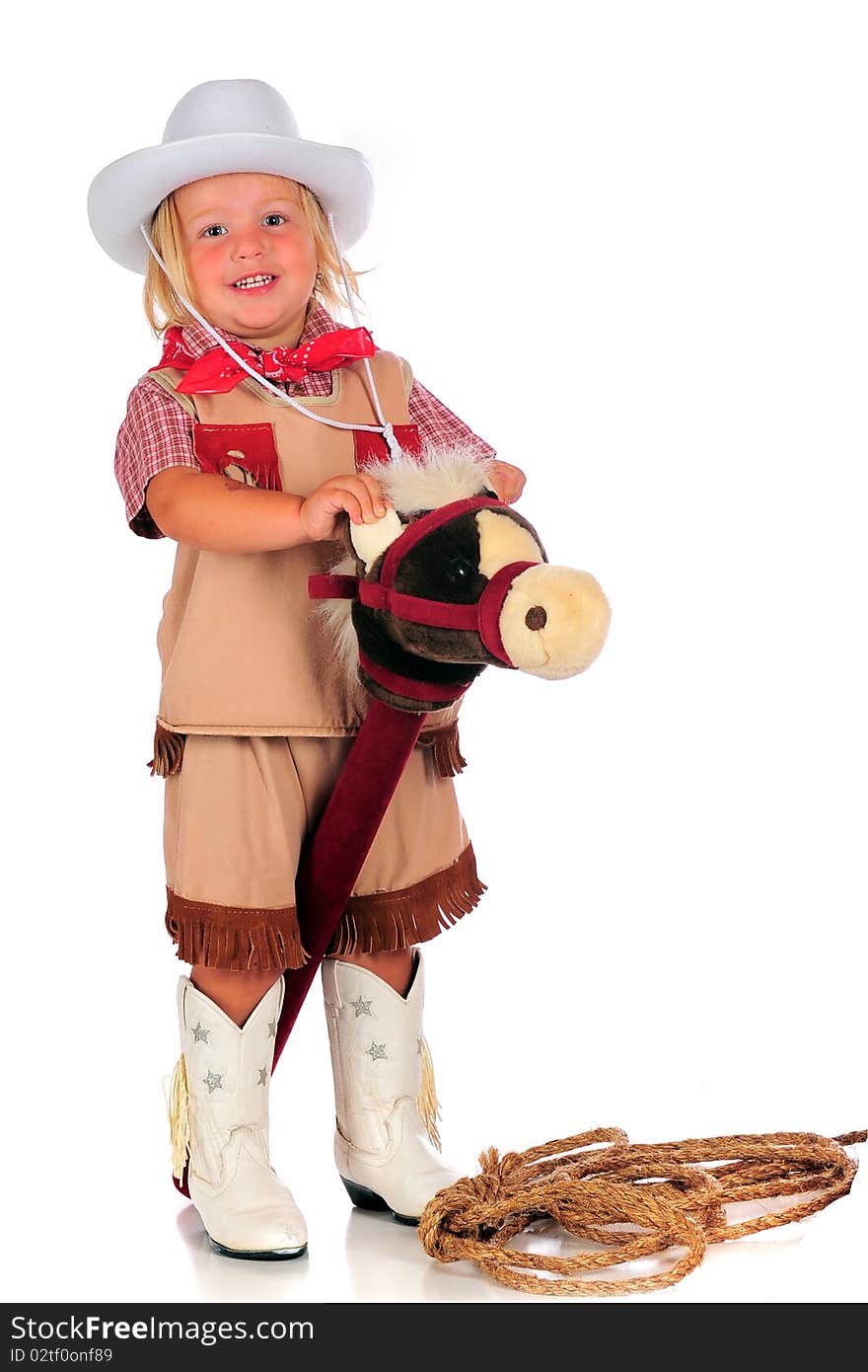 An adorable 2-year-old cowgirl riding her stick-horse by holding his ears. Isolated on white. An adorable 2-year-old cowgirl riding her stick-horse by holding his ears. Isolated on white.