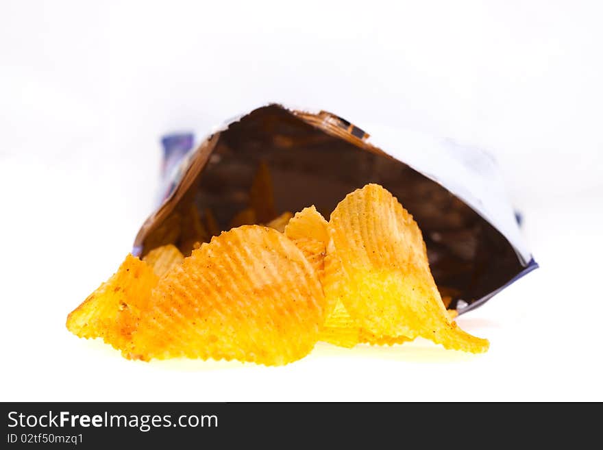 Spiced golden chips pile with the bag on white background
