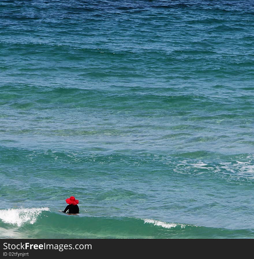 Senior lady with a big red hat enjoying dipping in the beautiful sea. Senior lady with a big red hat enjoying dipping in the beautiful sea