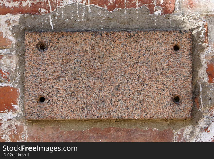 Old brick wall with a blank marble slab