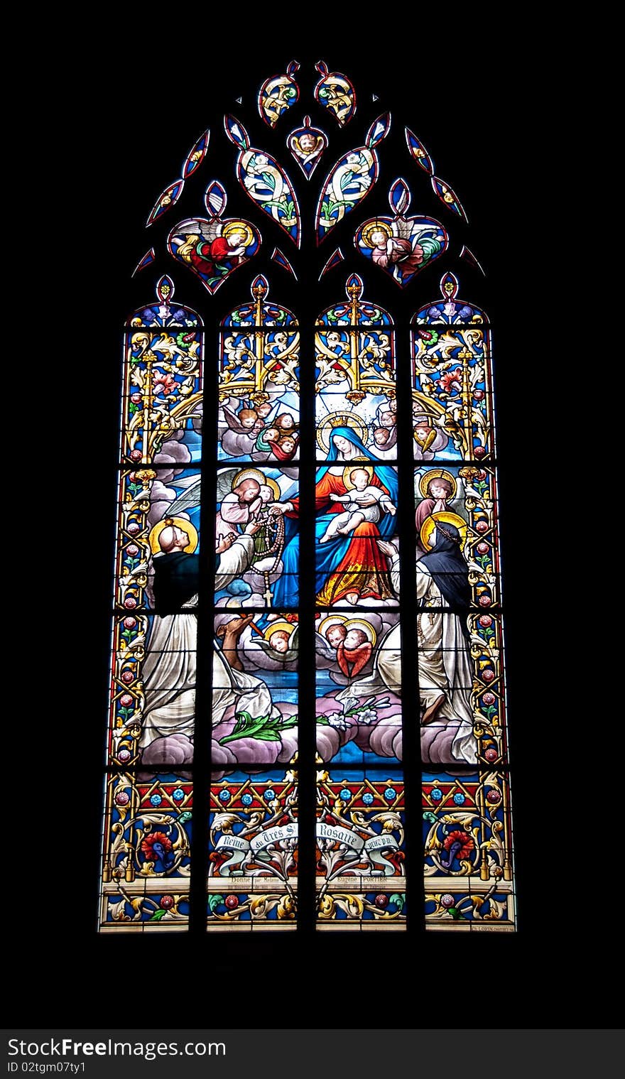 Stained glass window in a church showing a religious scene. St Dominic and St Rita receiving the rosary beads from the Blessed Virgin. Stained glass window in a church showing a religious scene. St Dominic and St Rita receiving the rosary beads from the Blessed Virgin.