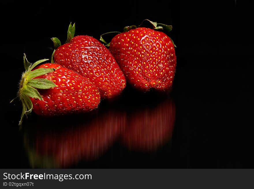 Three red strawberries on black background. Three red strawberries on black background