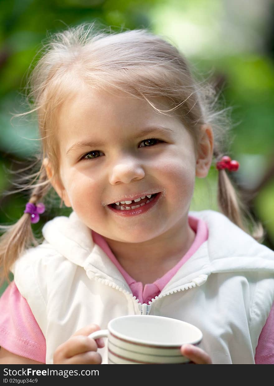 Little girl with milk cup and  have milk moustache standing outdoor. Little girl with milk cup and  have milk moustache standing outdoor