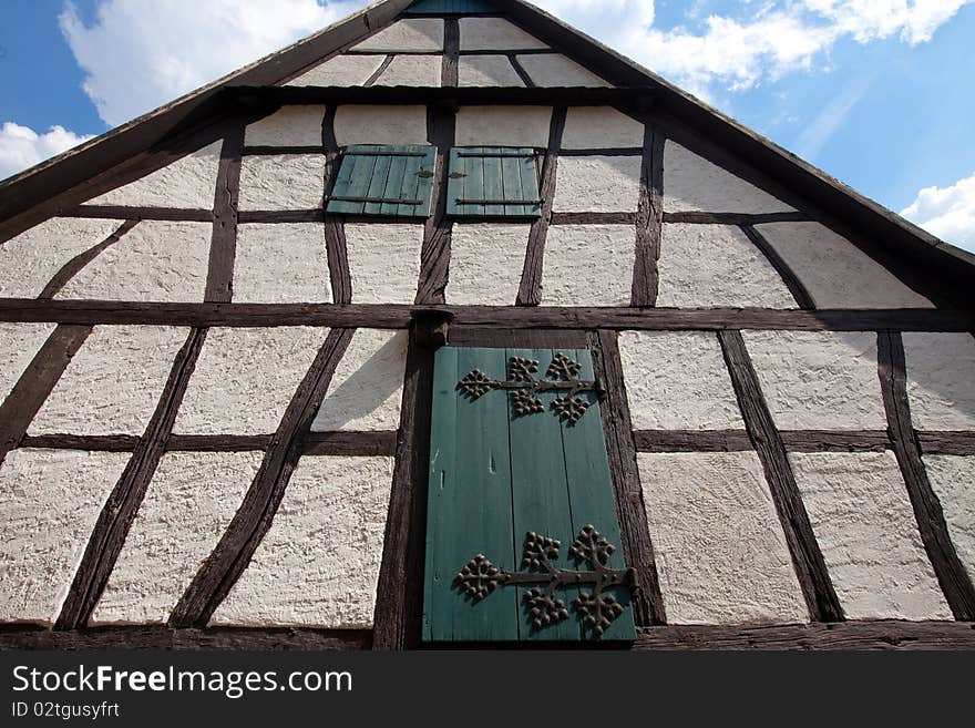Architectural detail of half-timbered framework constructed home in Europe (Germany) complete with window shutters with ornate wrought iron hinges. Architectural detail of half-timbered framework constructed home in Europe (Germany) complete with window shutters with ornate wrought iron hinges