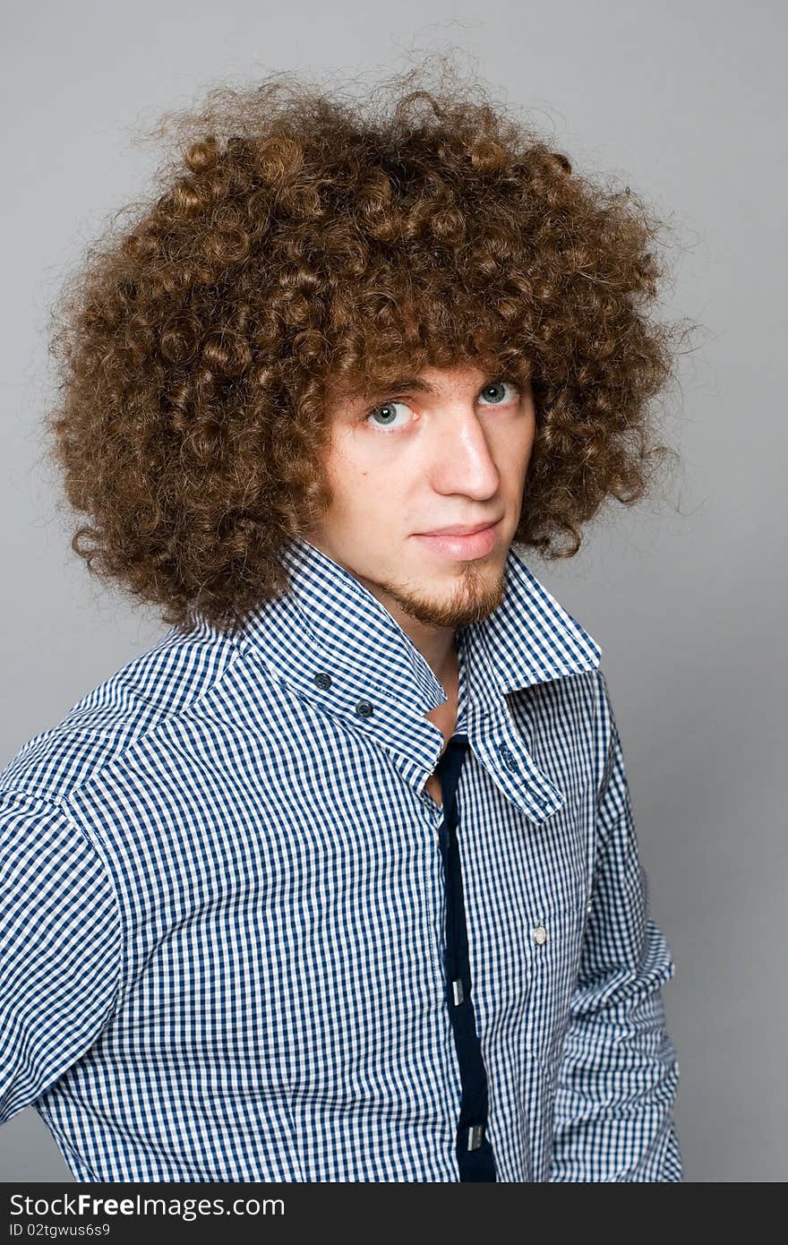 Young man with a curly hair on a gray background