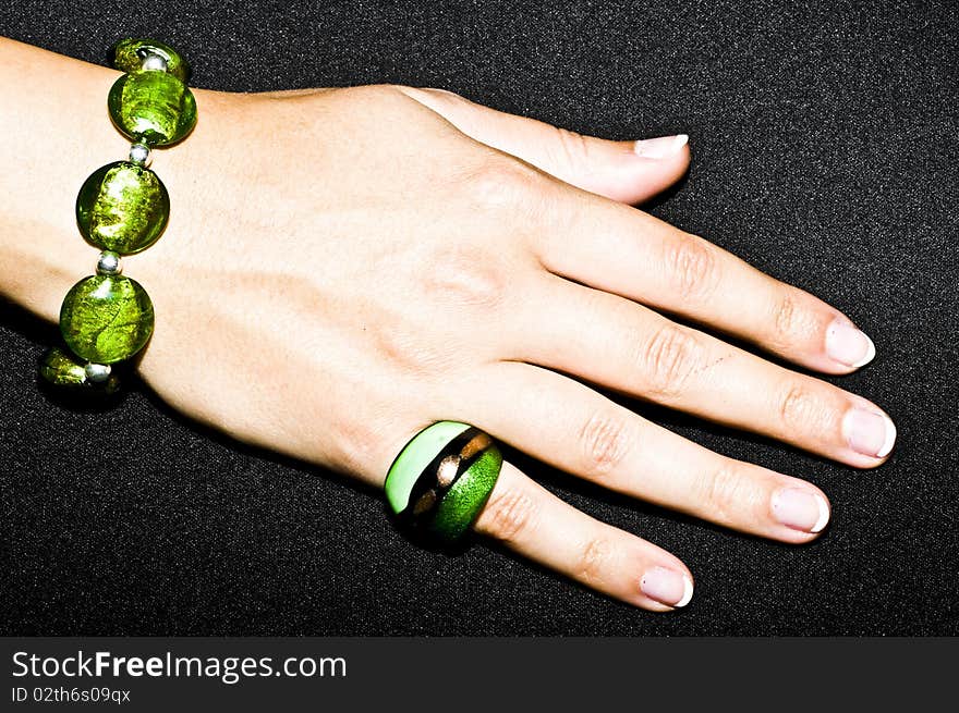 Green emerald bracelet and ring on woman hand, isolated on black background