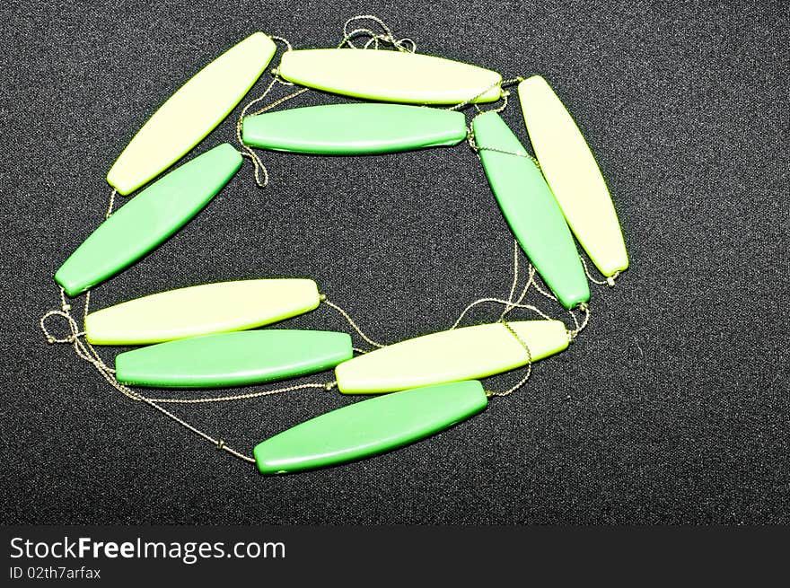 Green and yellow wooden necklace on black background