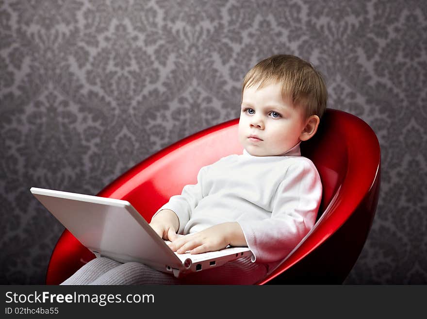 Image of boy sitting in a chair with a laptop