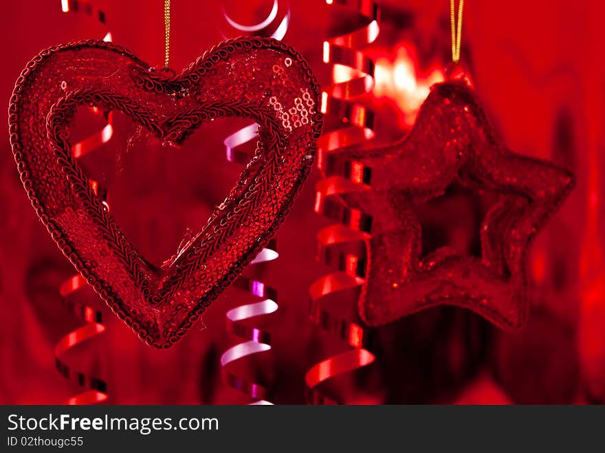 Red christmas baubles and ribbons on red background. Focus on heart. Red christmas baubles and ribbons on red background. Focus on heart