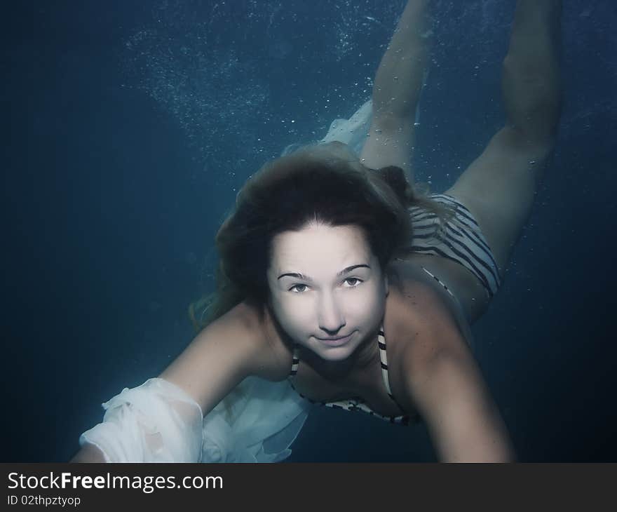 Young woman as a mermaid swimming underwater