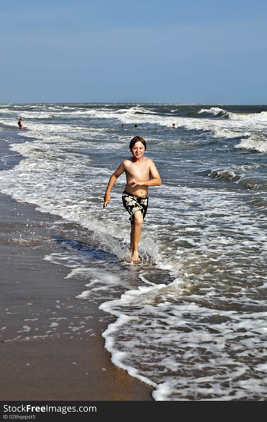 Boy running along the beautiful beach in the waves