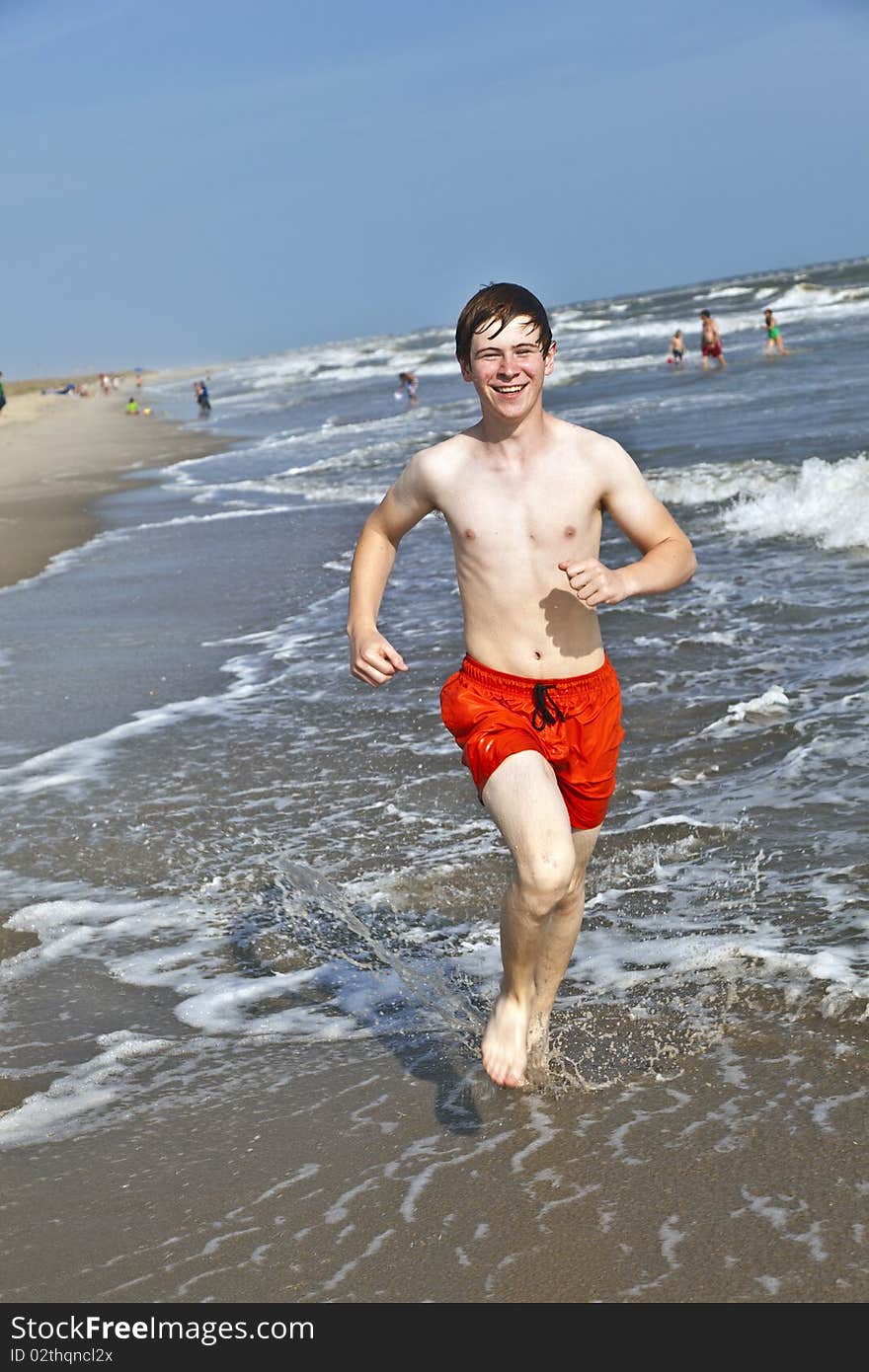 Boy running along the beautiful beach in the waves