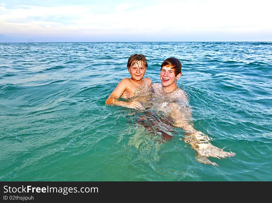 Brother holds his younger brother in his arms in the ocean. Brother holds his younger brother in his arms in the ocean