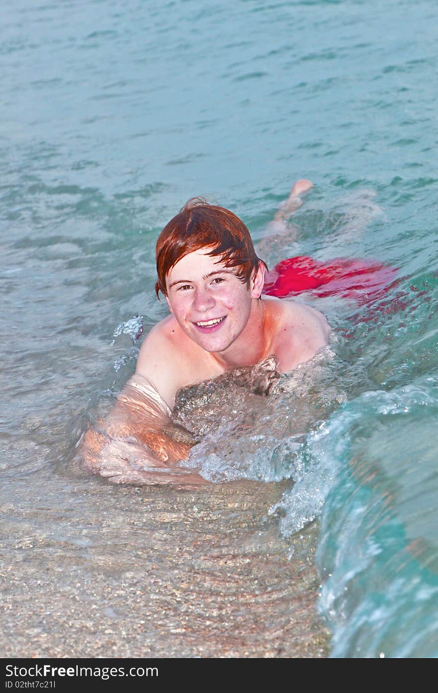 Young boy lying at the beach enjoys the surf of the ocean. Young boy lying at the beach enjoys the surf of the ocean