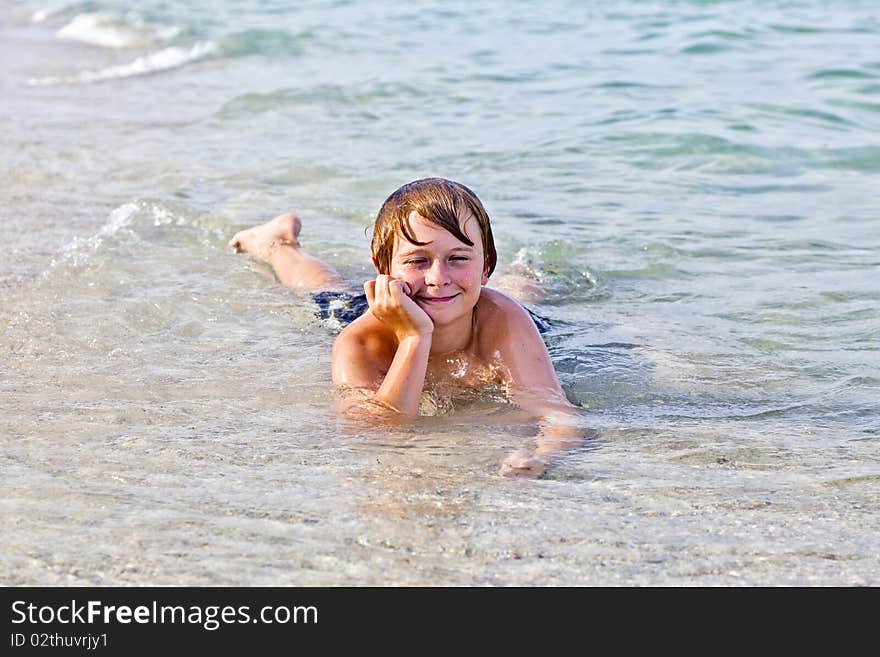 Boy Enjoys Lying At The Beach In The Surf