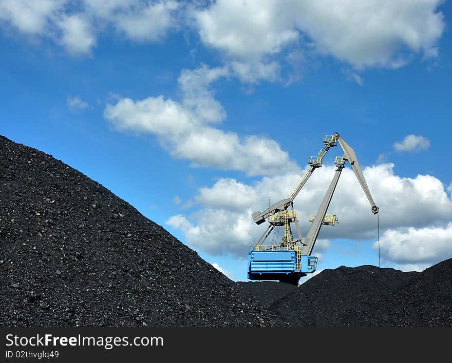 Crane loading coal against blue sky