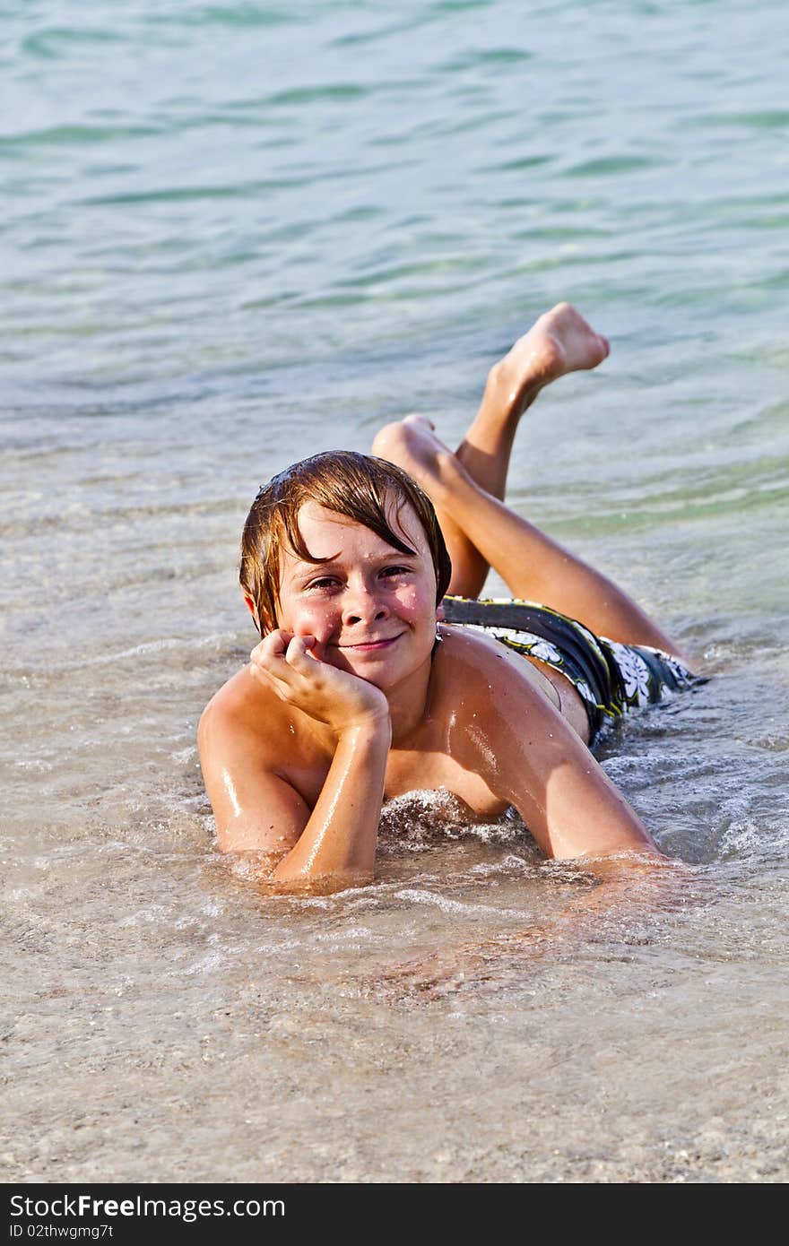 Boy Enjoys Lying At The Beach In The Surf