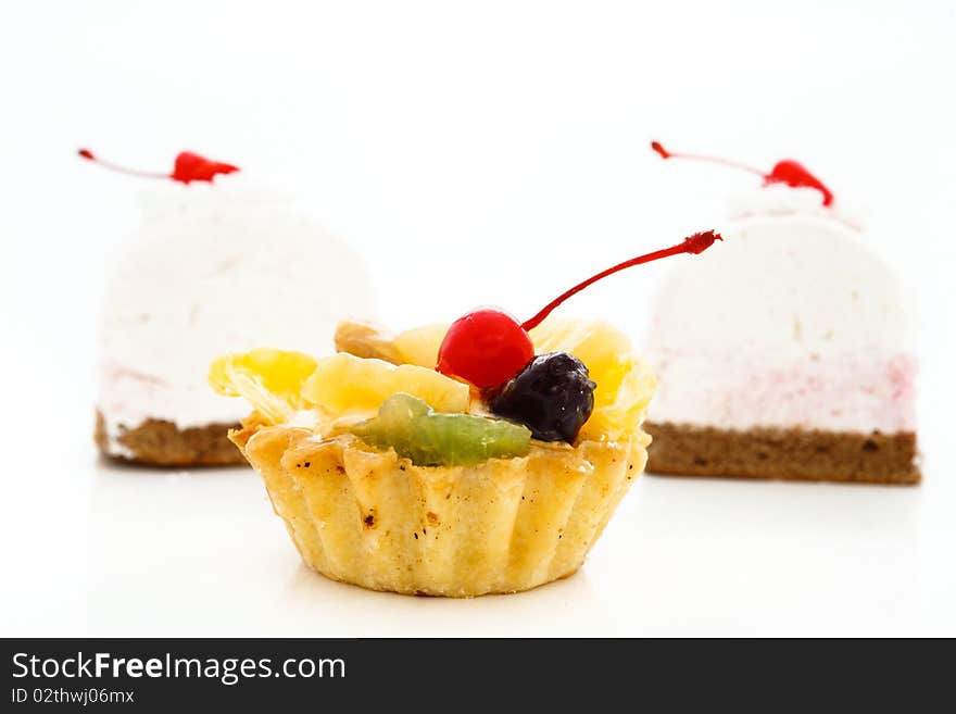 An image of cakes with cherry on top. On white background.