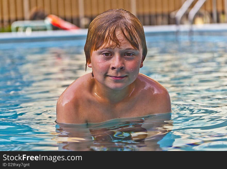 Boy enjoys swimming in an outdoor pool. Boy enjoys swimming in an outdoor pool