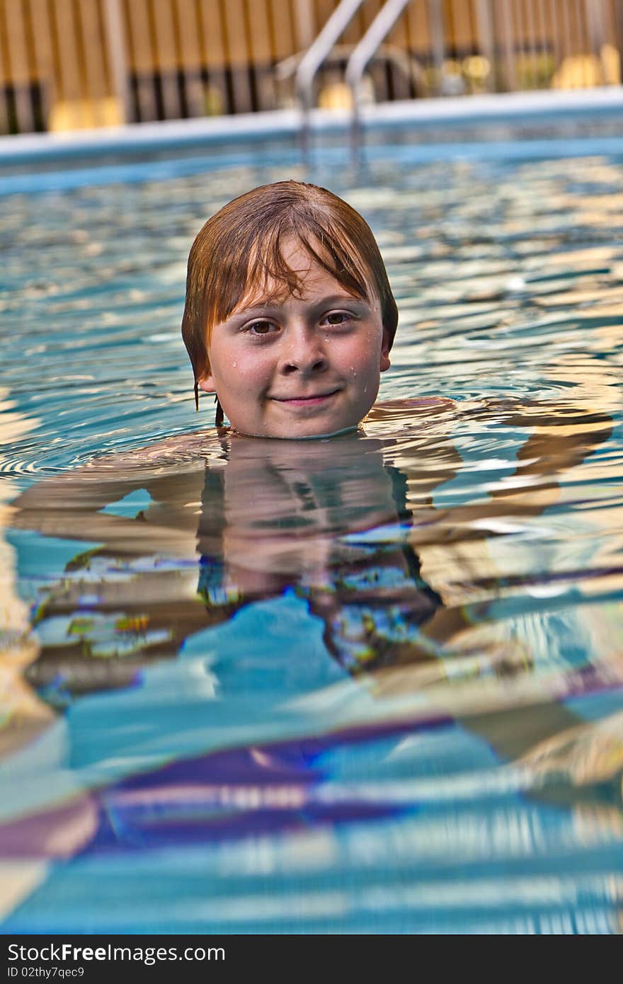 Boy enjoys swimming in an outdoor pool. Boy enjoys swimming in an outdoor pool