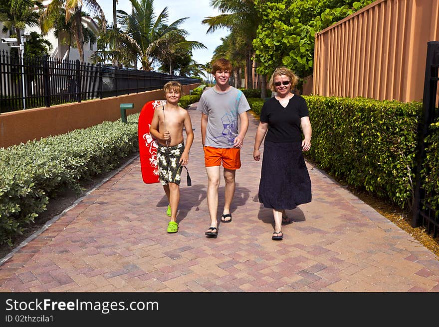 Mother with two sons on the way to the beach with beach equipment