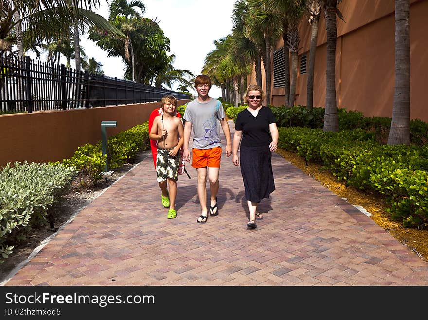 Mother with two sons on the way to the beach with beach equipment