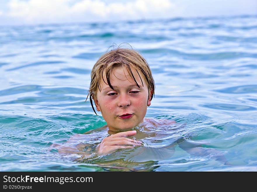 Child is swimming late afternoon in the ocean. Child is swimming late afternoon in the ocean