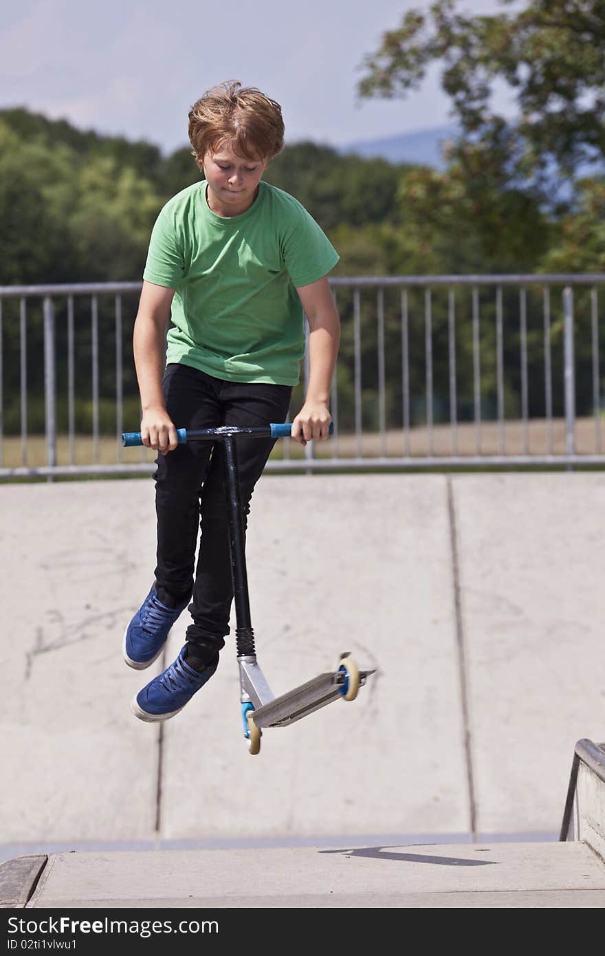 Young boy going airborne with his scooter at the skate park