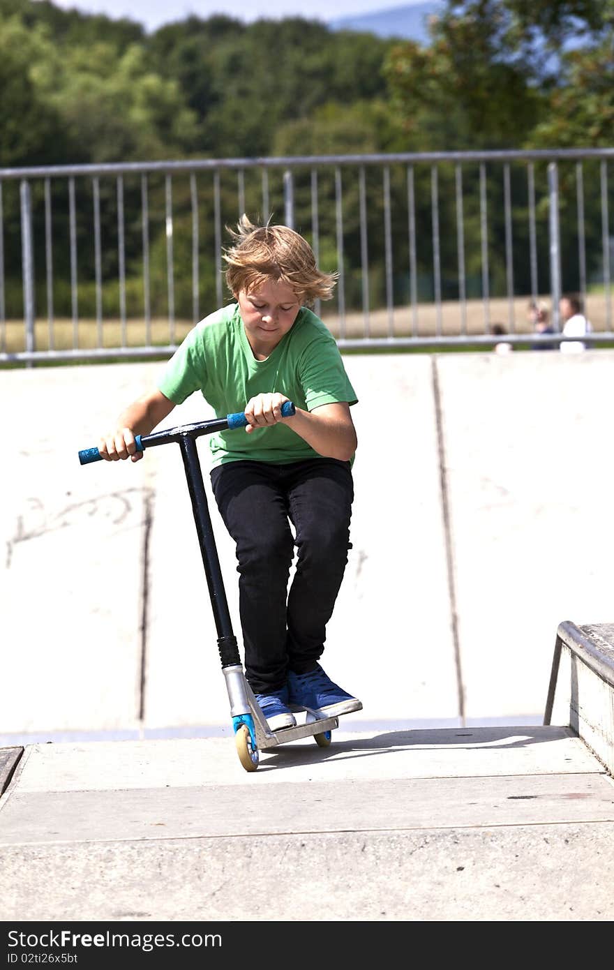 Young boy going airborne with his scooter at the skate park