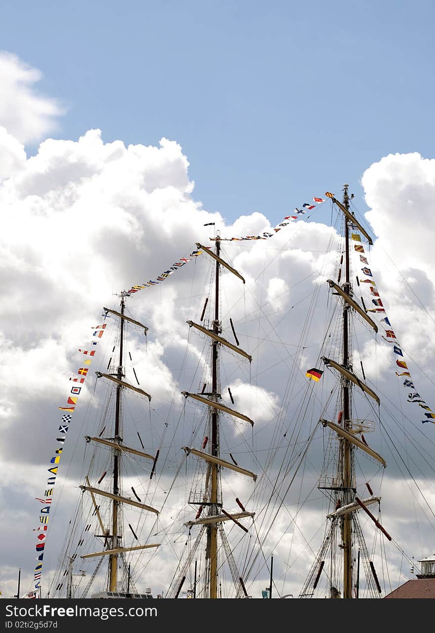 Masts of a bark and many flags with cloudy blue sky in the back. Masts of a bark and many flags with cloudy blue sky in the back