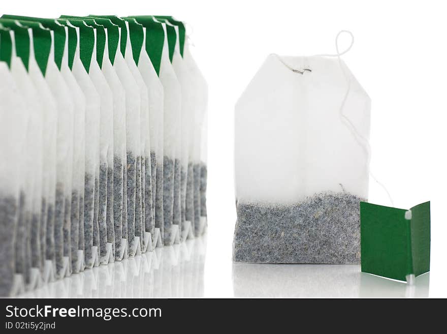 A row of teabags and one aside isolated over white.