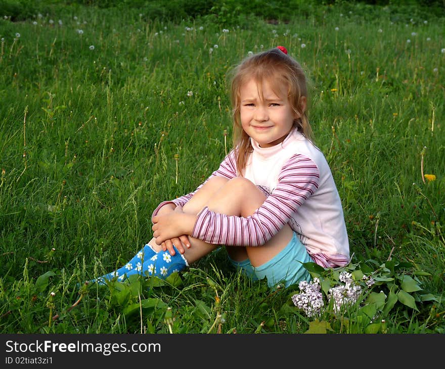 Red-haired girl with a bouquet of lilacs lay on the grass.