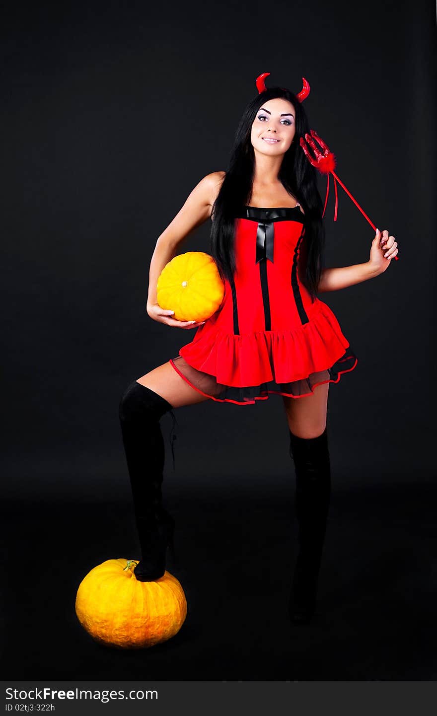 young brunette woman dressed as an imp with pumpkins