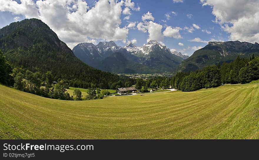 Wide angle panorama landscape taken in Lofer, Austria. A light green field in the foreground, mountains in the background and Lofer in between. Wide angle panorama landscape taken in Lofer, Austria. A light green field in the foreground, mountains in the background and Lofer in between