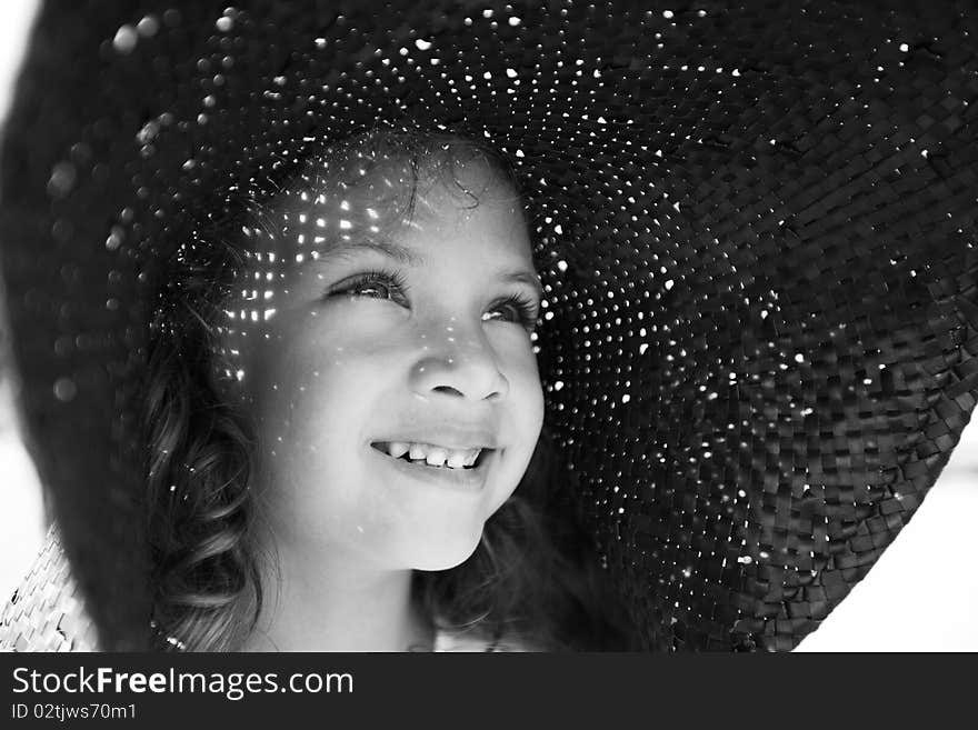 Monocrome close-up portrait of a pretty little smiling girl in a wide hat in a sunny summer day. Monocrome close-up portrait of a pretty little smiling girl in a wide hat in a sunny summer day