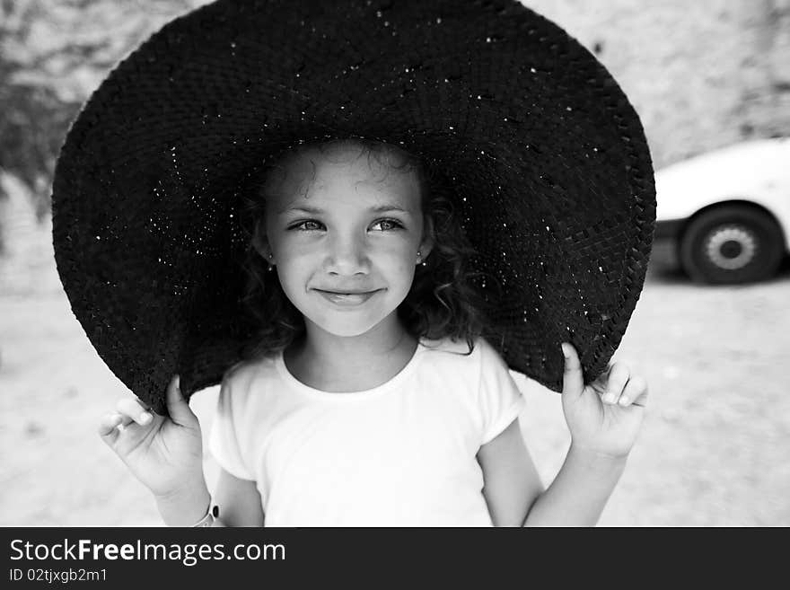 Outdoor portrait of a beautiful little girl in a wide hat