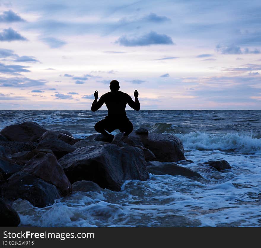 Man meditating on a stony sea shore