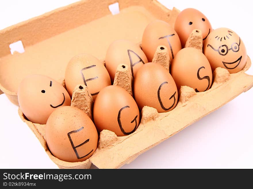 Eggs with an inscription EAT EGGS and some eggs with smiling faces in a carton