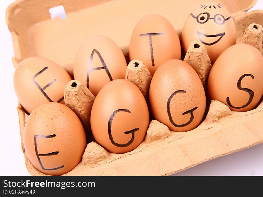 Eggs with an inscription EAT EGGS and an egg with a smiling face in an egg carton