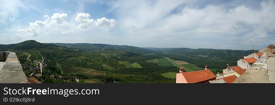 Panoramic landscape consisting of mountains, forests and sky with clouds