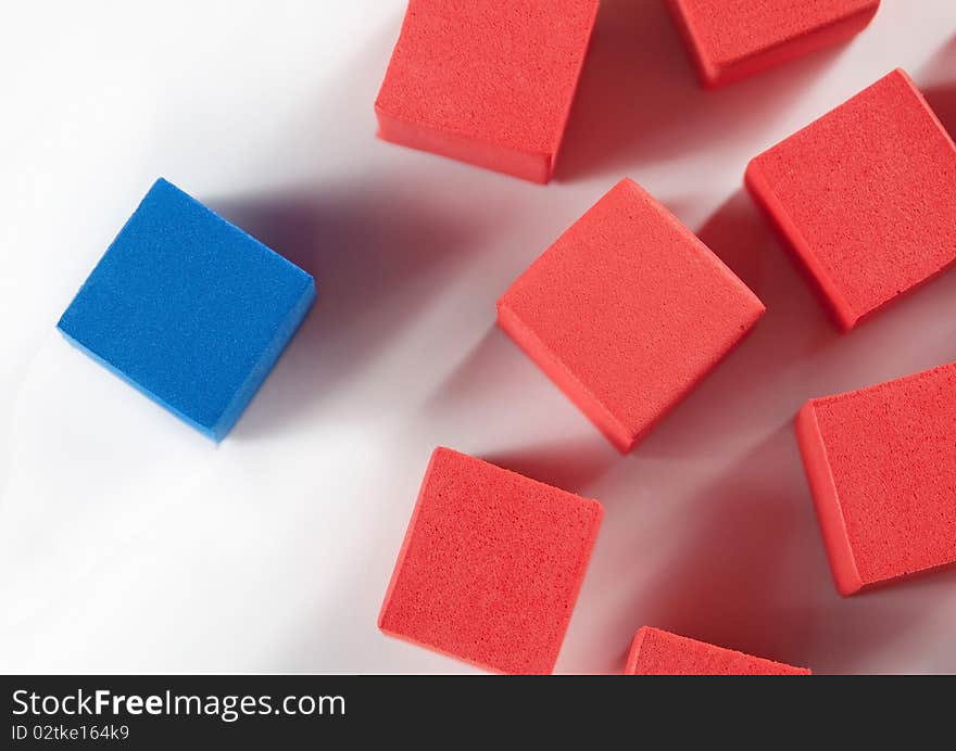 One blue block stands apart from a group of scattered orange blocks. One blue block stands apart from a group of scattered orange blocks