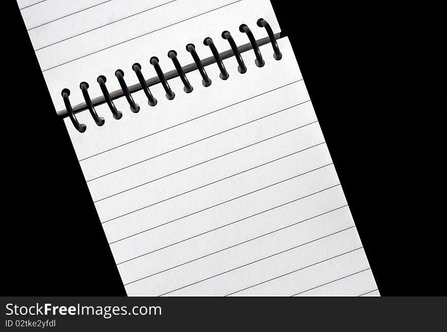 An open wire bound notebook with blank lined pages on a clean black background. An open wire bound notebook with blank lined pages on a clean black background